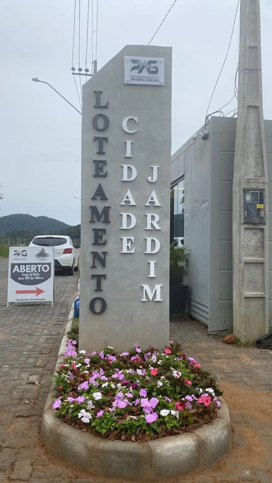 Totem de entrada do Loteamento Cidade Jardim, com um canteiro de flores na base.