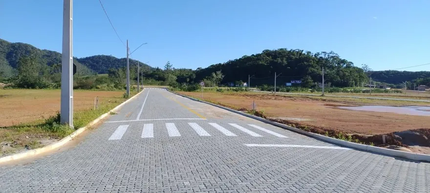Cruzamento com faixa de pedestres no Loteamento Cidade Jardim I, com um morro ao fundo.