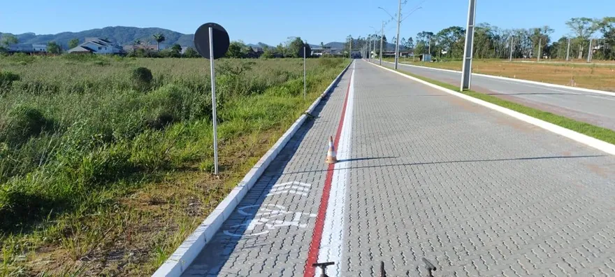 Rua pavimentada do Loteamento Cidade Jardim I com faixa vermelha junto ao meio-fio e gramado ao lado.
