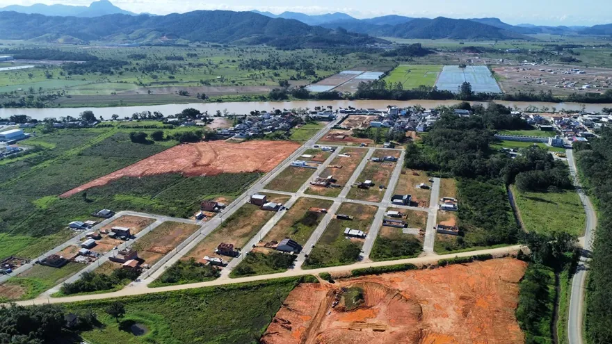 Vista aérea do Loteamento Cidade Jardim I visto de longe, com campos e morros ao fundo.