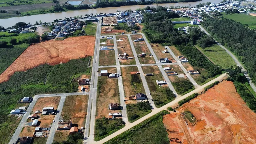 Vista aérea do Loteamento Cidade Jardim I, com ruas, lotes e construções, e áreas de terra ao lado.