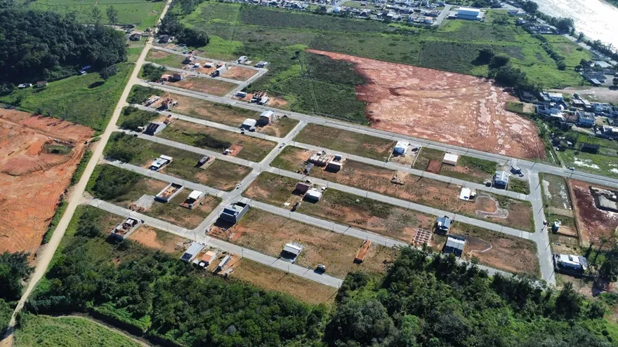 Vista aérea do Loteamento Cidade Jardim I, com as ruas em grade, mata embaixo e uma área de terra ao fundo.